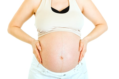 Pregnant woman holding her belly isolated on white. Close-up.
